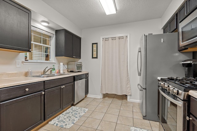 kitchen featuring light tile patterned floors, a sink, light countertops, appliances with stainless steel finishes, and a textured ceiling