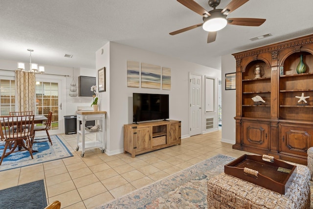 living room with visible vents, baseboards, light tile patterned floors, a textured ceiling, and ceiling fan with notable chandelier