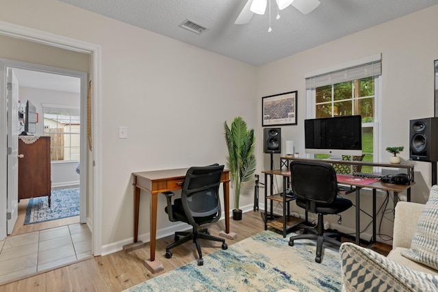 home office with wood finished floors, visible vents, and a healthy amount of sunlight