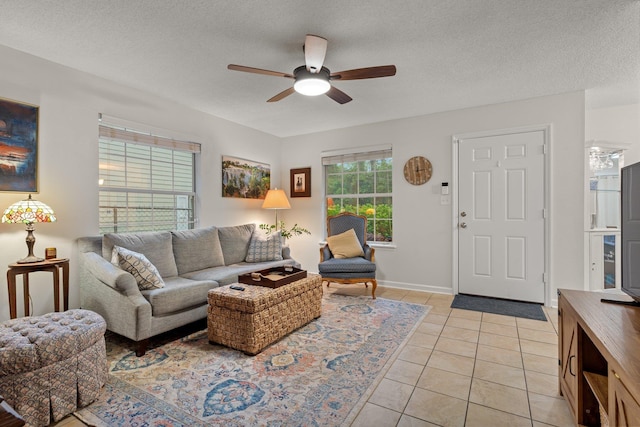 living room featuring ceiling fan, light tile patterned flooring, baseboards, and a textured ceiling