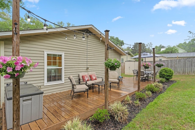 wooden terrace with a storage shed, outdoor lounge area, an outdoor structure, a lawn, and fence