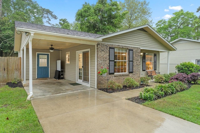 view of front facade featuring ceiling fan, a carport, fence, a front lawn, and driveway