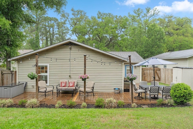 rear view of house with a yard, fence, a deck, and an outbuilding