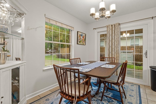 dining space with a chandelier, a textured ceiling, light tile patterned floors, and baseboards