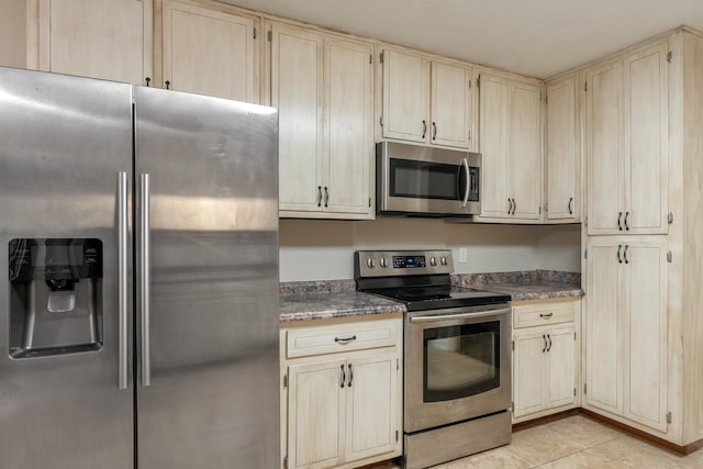 2214 Yaupon Dr, Tallahassee, FL 32303 - kitchen featuring stainless steel appliances, light tile patterned flooring, dark countertops, and cream cabinets