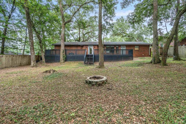 2214 Yaupon Dr, Tallahassee, FL 32303 - rear view of property featuring an outdoor fire pit, brick siding, a deck, and a fenced backyard