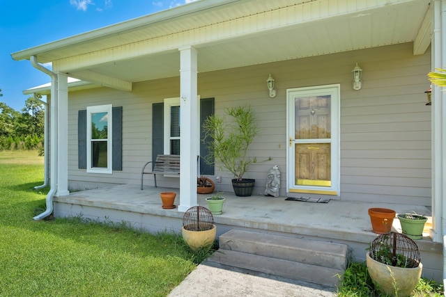 entrance to property featuring a porch and a lawn