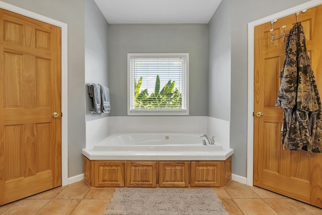 bathroom with tile patterned floors, a bath, and baseboards