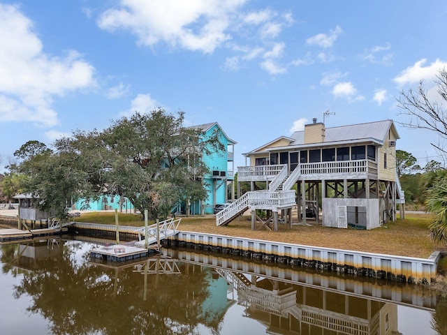 back of house featuring a sunroom and a water view