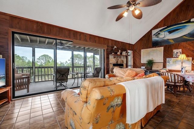 tiled living room with high vaulted ceiling, ceiling fan, and wood walls