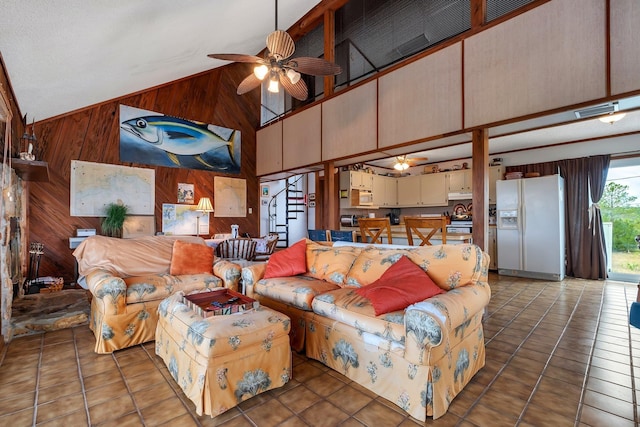 living room featuring ceiling fan, dark tile patterned flooring, high vaulted ceiling, and wood walls