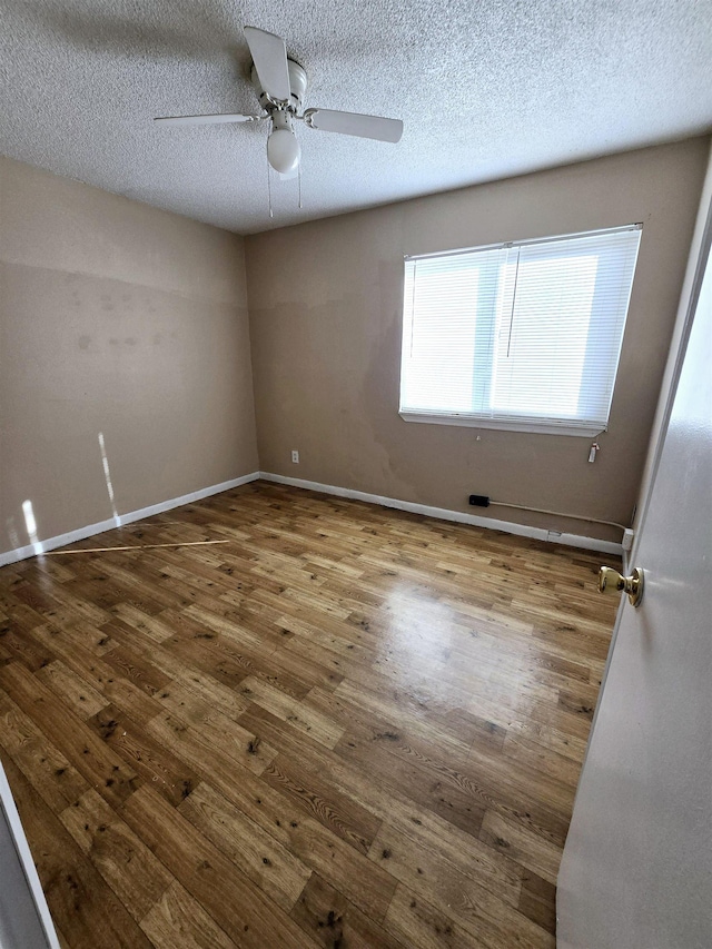 empty room with a textured ceiling, wood-type flooring, and ceiling fan