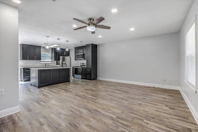 kitchen with light wood-style flooring, stainless steel appliances, a healthy amount of sunlight, open floor plan, and light countertops