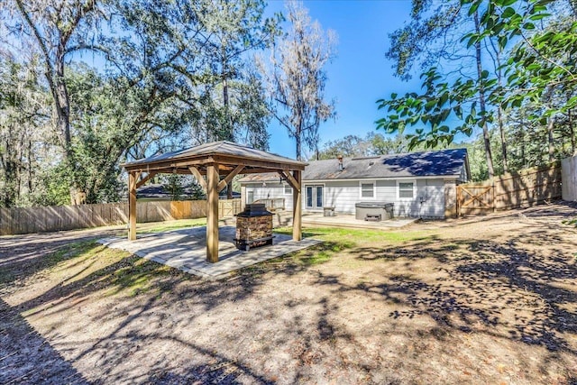 view of yard featuring a patio area, a fenced backyard, a hot tub, and a gazebo