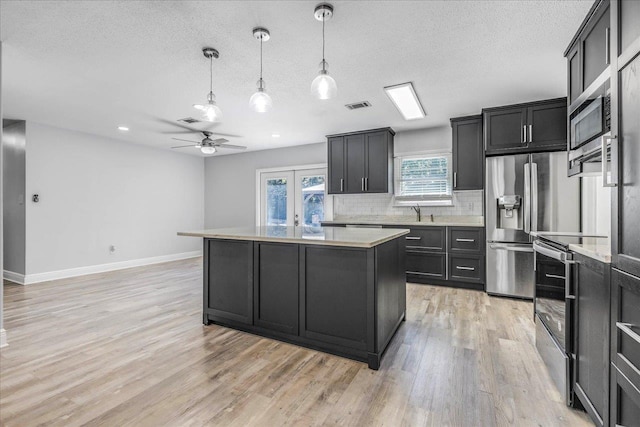 kitchen with visible vents, light wood finished floors, french doors, a center island, and tasteful backsplash