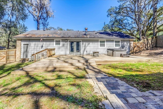 back of property featuring french doors, brick siding, a hot tub, fence, and a wooden deck