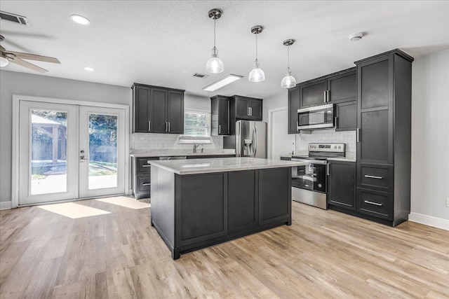 kitchen featuring stainless steel appliances, visible vents, french doors, light wood-type flooring, and a center island