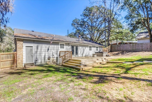 rear view of house with a deck, a fenced backyard, brick siding, a yard, and french doors