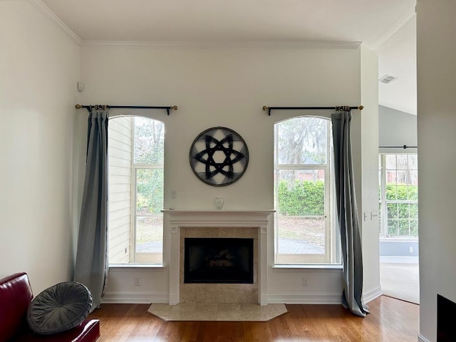 unfurnished living room featuring visible vents, ornamental molding, a fireplace, and wood finished floors