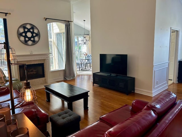 living area featuring a high end fireplace, a notable chandelier, lofted ceiling, and wood finished floors