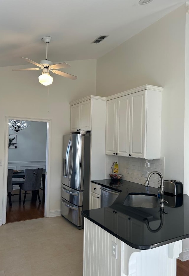 kitchen featuring white cabinetry, dark countertops, stainless steel fridge with ice dispenser, and a sink