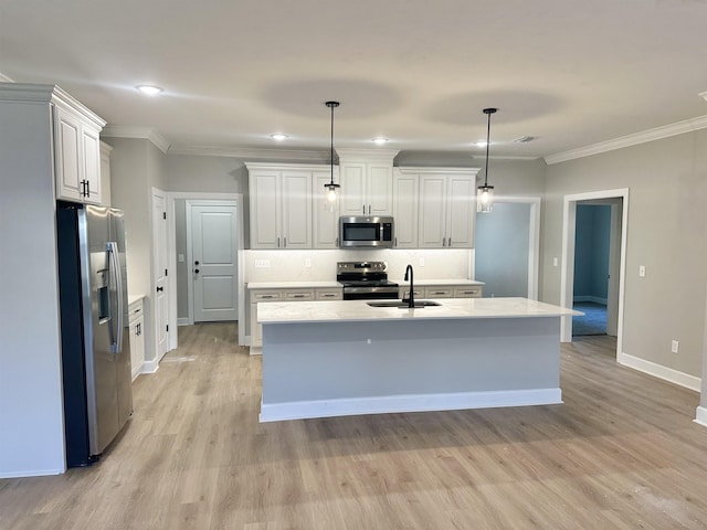 kitchen featuring appliances with stainless steel finishes, sink, white cabinetry, hanging light fixtures, and an island with sink