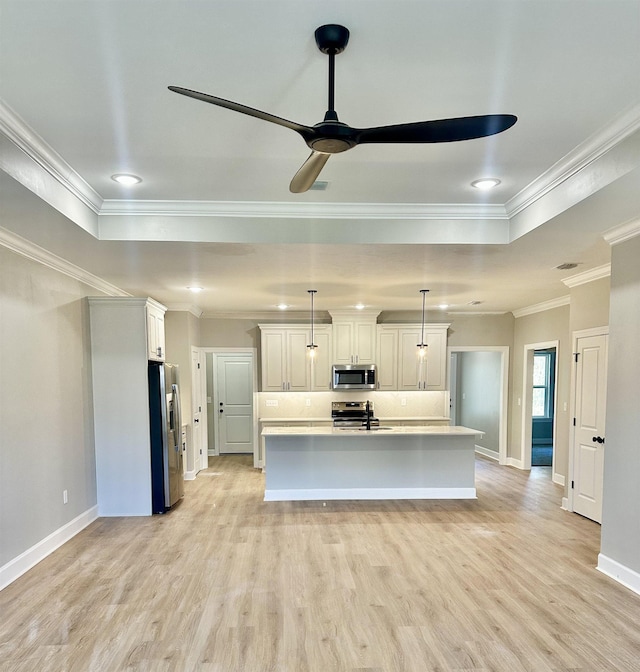 kitchen with appliances with stainless steel finishes, decorative light fixtures, white cabinets, light hardwood / wood-style floors, and an island with sink