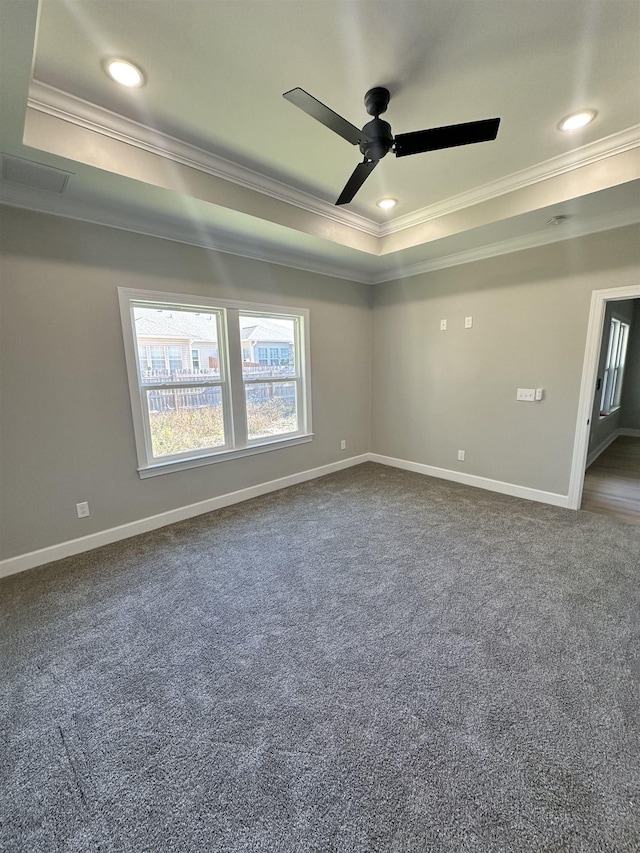 spare room featuring ceiling fan, dark carpet, a raised ceiling, and ornamental molding