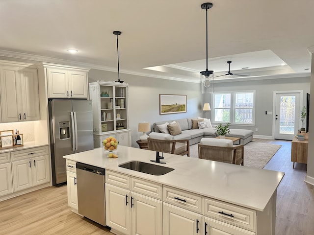 kitchen with appliances with stainless steel finishes, a tray ceiling, ceiling fan, decorative light fixtures, and light hardwood / wood-style floors