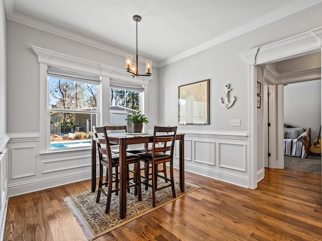 dining area featuring dark wood-type flooring, crown molding, and a notable chandelier