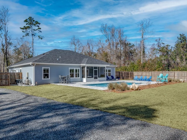 back of property with a fenced in pool, a patio, a sunroom, and a lawn