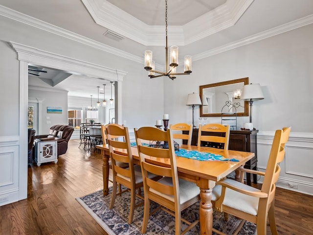 dining area with crown molding, a raised ceiling, and a chandelier