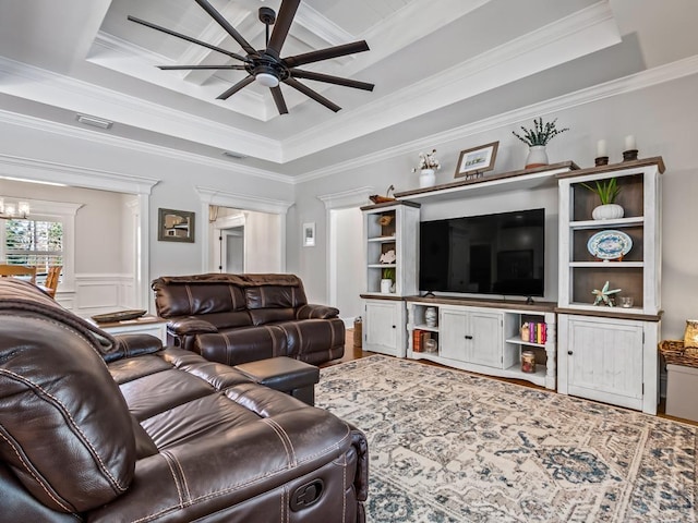 living room with a raised ceiling and crown molding