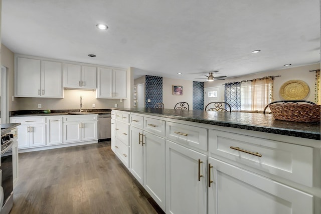 kitchen with dishwasher, dark countertops, wood finished floors, white cabinetry, and a sink