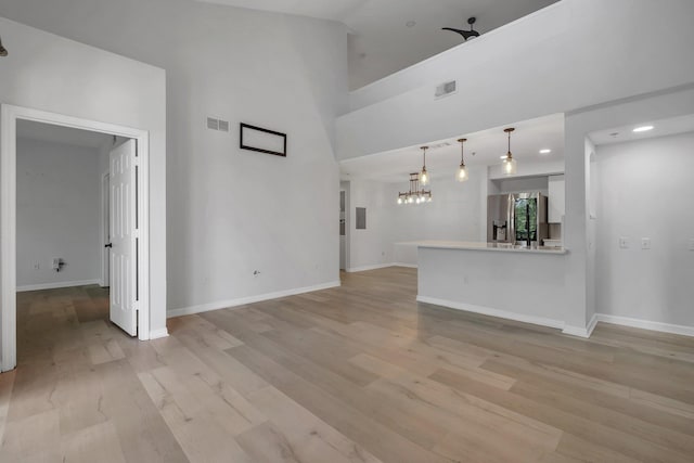 2801 Chancellorsville Dr Unit 236, Tallahassee, FL 32312 - unfurnished living room featuring a chandelier, light wood-style floors, baseboards, and a high ceiling