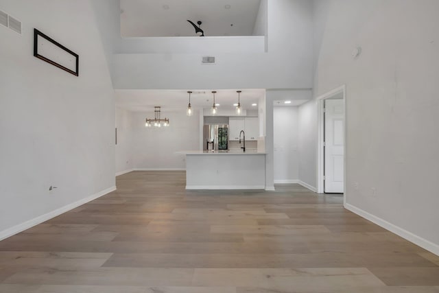 2801 Chancellorsville Dr Unit 236, Tallahassee, FL 32312 - unfurnished living room with a sink, a high ceiling, light wood-type flooring, baseboards, and a chandelier