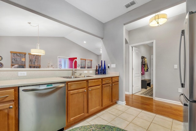 kitchen featuring lofted ceiling, sink, decorative light fixtures, light tile patterned floors, and stainless steel appliances