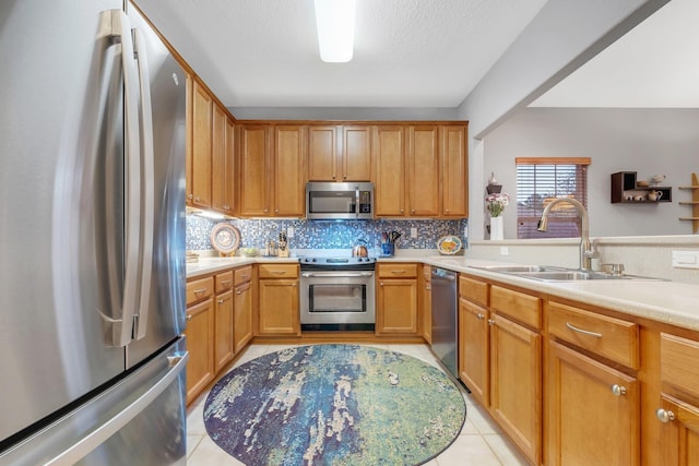 kitchen with sink, a textured ceiling, light tile patterned floors, stainless steel appliances, and decorative backsplash