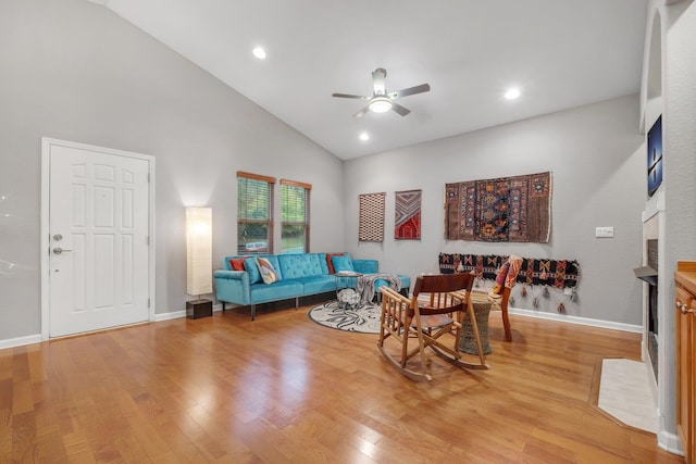 living room featuring high vaulted ceiling, ceiling fan, and light wood-type flooring