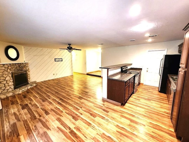 2405 Lanrell Dr, Tallahassee, FL 32303 - kitchen with stainless steel appliances, open floor plan, light wood-type flooring, a stone fireplace, and wooden walls