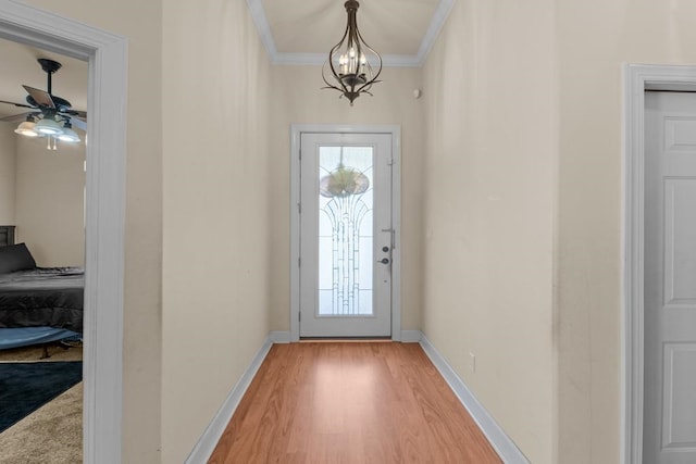 doorway with light hardwood / wood-style floors, ceiling fan with notable chandelier, and crown molding