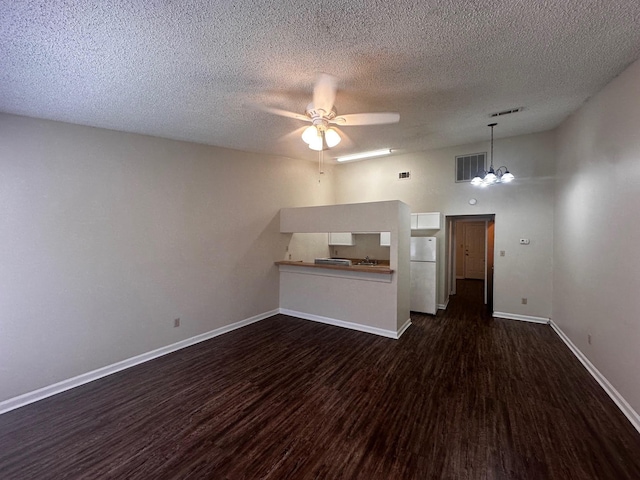 unfurnished living room with a textured ceiling, ceiling fan with notable chandelier, and dark wood-type flooring