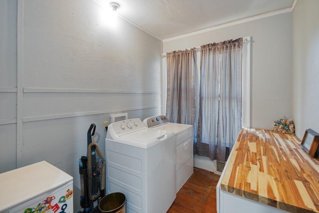 clothes washing area featuring separate washer and dryer, crown molding, and dark wood-type flooring