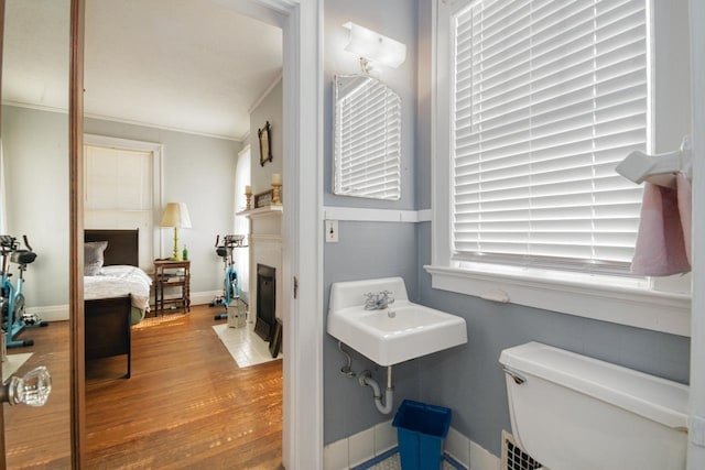 bathroom with hardwood / wood-style flooring, toilet, and crown molding