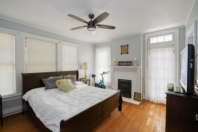 bedroom featuring hardwood / wood-style flooring, ceiling fan, crown molding, and a textured ceiling