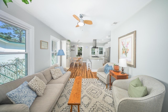 living room with a healthy amount of sunlight, baseboards, a ceiling fan, and wood finished floors