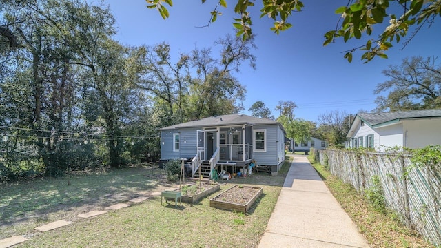 view of front facade featuring fence, a front yard, and a garden