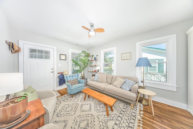 living area featuring wood finished floors, baseboards, and ceiling fan