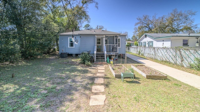 rear view of house featuring central air condition unit, a garden, fence, and a lawn