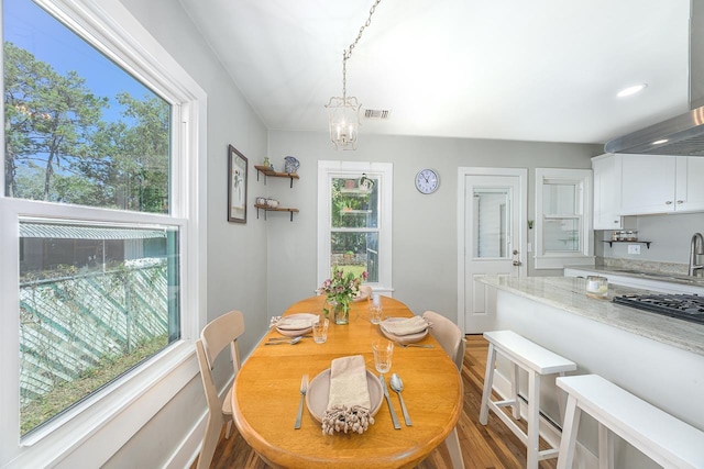 dining space featuring visible vents, an inviting chandelier, and wood finished floors